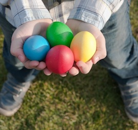 child holding four colored Easter eggs